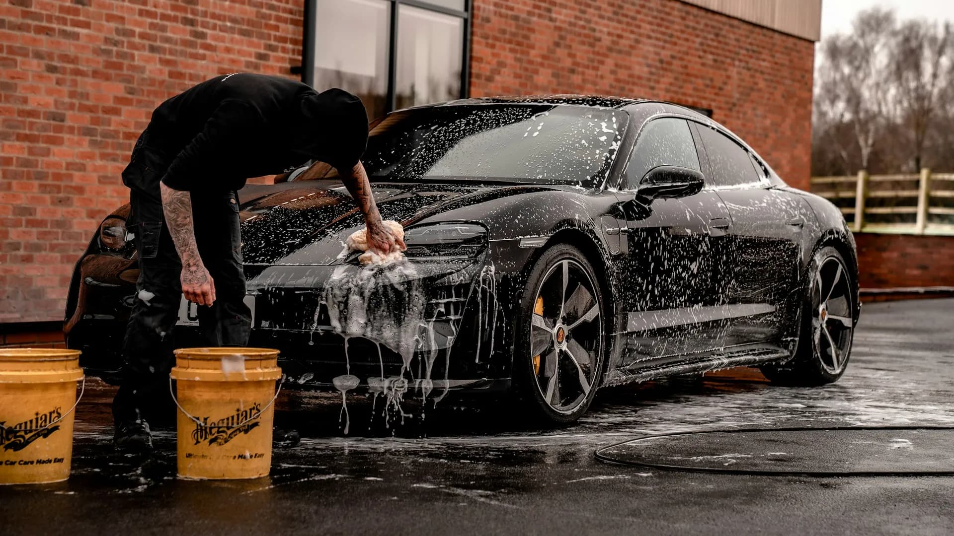 Lavage à la main d’une voiture noire recouverte de mousse