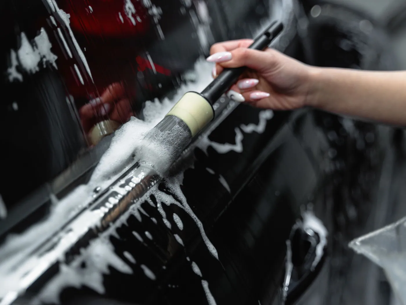 Brosse de detailing sur une carrosserie noire brillante